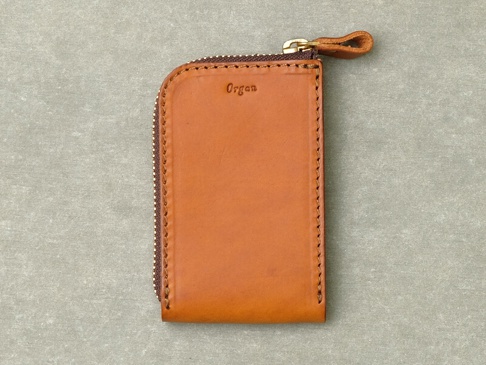 職人手作的卡其色皮革拉鍊卡片鑰匙包，表面壓印有「Organ」字樣，搭配金色拉鍊及皮革拉環。