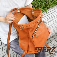 職人手作皮革後背包，採用棕褐色皮革，設有雙拉鍊前袋，內襯為淺棕色皮革，展示了其獨特的手工質感與設計。