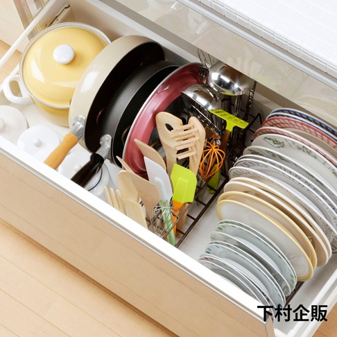 一個裝有鍋具、平底鍋、盤子和廚房用具的白色抽屜，抽屜內有一個金屬製的伸縮式收納架，架上整齊地擺放著各種廚具，顏色包含黃色、米色、黑色、紅色、木色和綠色。