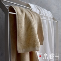 TAFFUL強悍耐洗速乾浴巾，展示一條米白色毛巾懸掛在白色毛巾架上，毛巾質地蓬鬆，邊緣有縫線。另一條白色浴巾在後方。