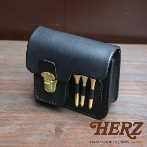 黑色皮革高爾夫腰包，附有金色金屬扣和三個木質高爾夫球釘，收納於前方皮帶中。