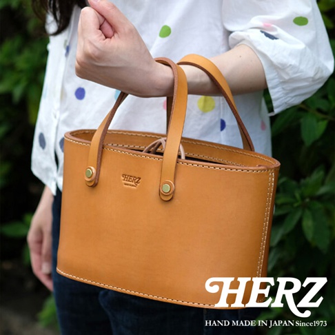 棕色皮革束口手提包，有著雙提把和精緻的縫線，包身正面有品牌壓紋。