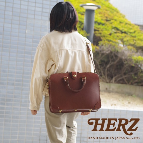 職人手作咖啡色皮革三層收納兩用商務公事包，配有頂部提把及可拆卸肩帶，金屬扣環與鉚釘裝飾。