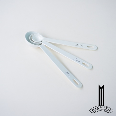 一套三個白色琺瑯量匙，分別標示 2.5cc、5cc 和 15cc，疊放在白色背景上。
