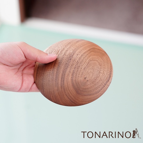 手持一顆圓形天然實木門擋，木紋清晰，顏色為溫潤的木棕色。