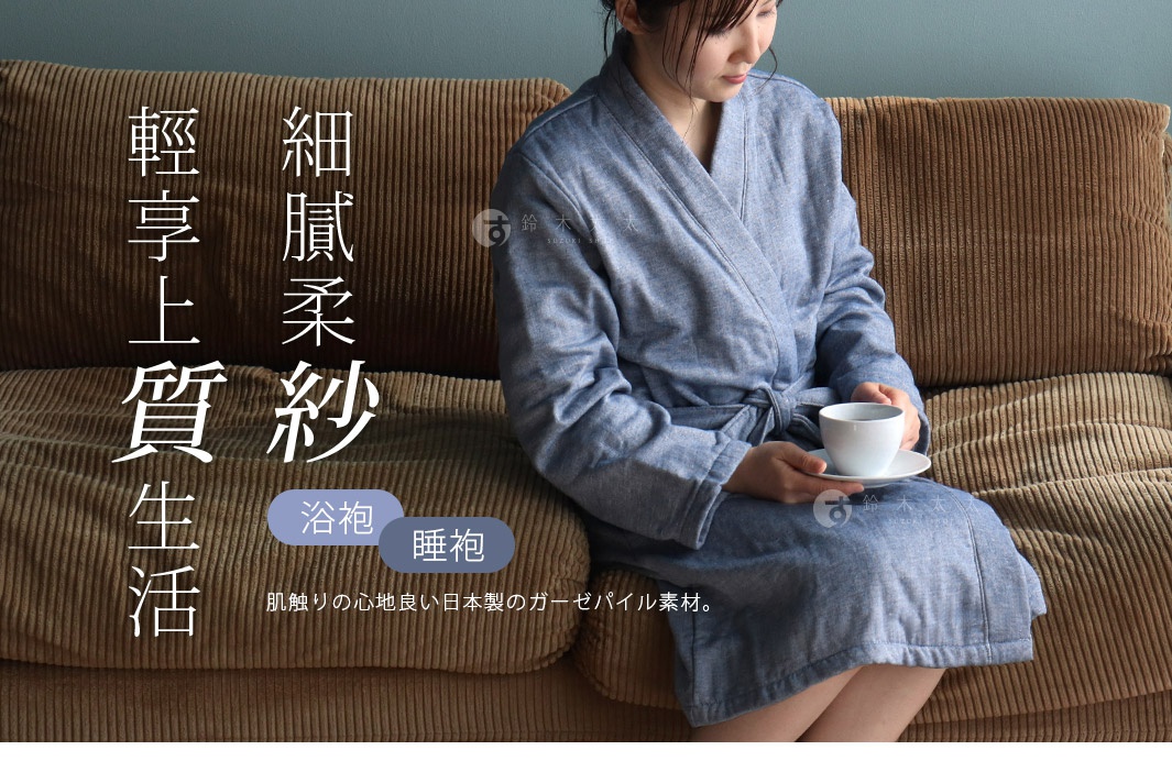一位女性身穿淺藍色異素材紗質輕柔瞬吸浴袍，坐在棕色燈芯絨沙發上，雙手捧著一杯白色馬克杯。
