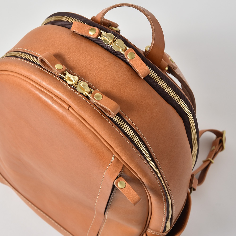 棕色皮革多功能後背包，有兩個前拉鍊口袋，金色拉鍊及皮革拉頭，雙肩帶可調節。