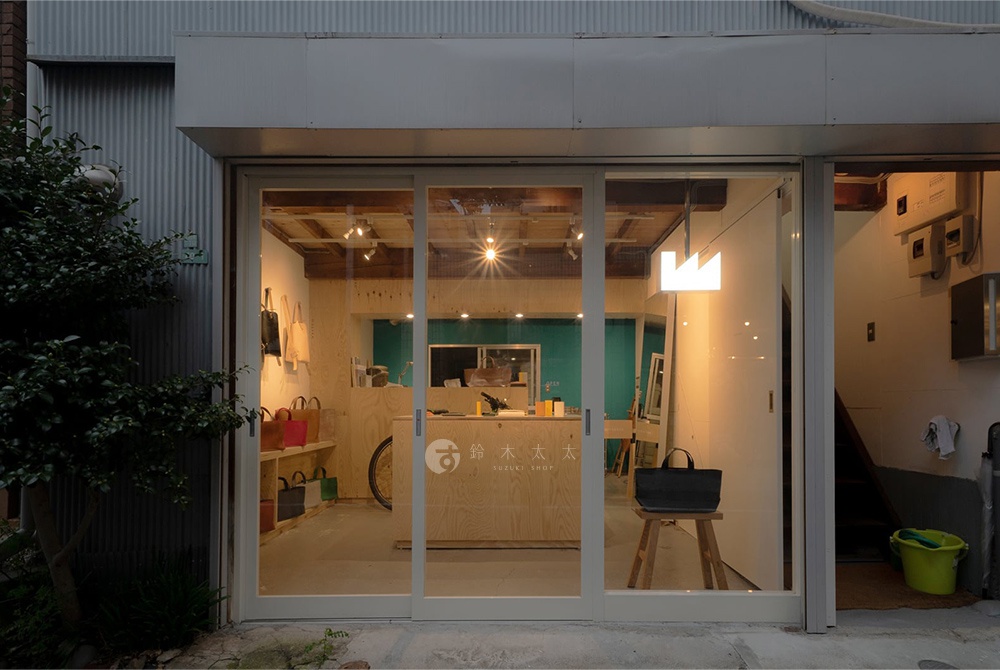 FABRIK 品牌店面入口，玻璃門內展示著皮件商品，店內有簡潔的木質櫃檯和貨架，櫃檯上有「SUZUKI SHOP」的字樣。