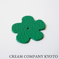 綠色皮革製作的四葉草造型吊飾，具有壓紋紋理，中央有一個小孔。