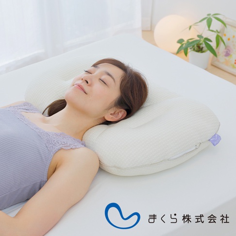 一位女子仰躺於米白色格紋布料的良夢調節枕上，枕頭呈現波浪狀曲線，中間凹陷，兩側隆起，支撐著女子的頭部與頸部。
