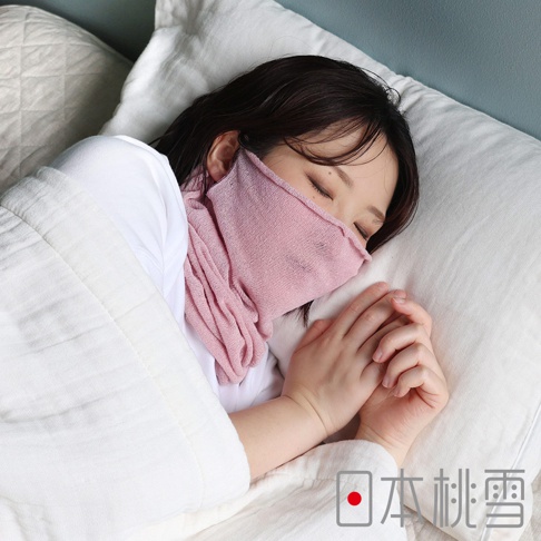 一位女性側身躺在白色枕頭上熟睡，她戴著粉紅色的針織睡眠口罩，遮住口鼻並延伸至頸部保暖，整體畫面呈現寧靜舒適的睡眠氛圍，右下角印有日本桃雪品牌字樣。