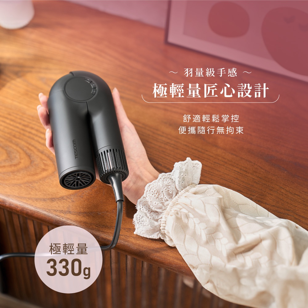 手持黑色 Tescom 摺疊吹風機，展示其輕巧的設計與羽量級手感，並標示極輕量 330g。