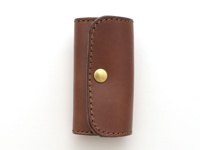 職人手作皮革經典鑰匙包，深棕色皮革，設有四個鑰匙鉤，以金色金屬按鈕固定。