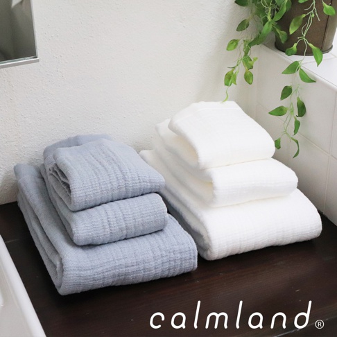 一疊淺藍色無撚紗質毛巾，旁邊疊著一疊白色無撚紗質毛巾，毛巾質地柔軟，有細緻的織紋。