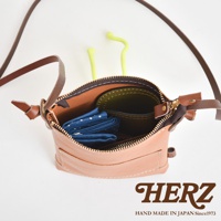 職人手作皮革直式隨身單肩包，淺棕色皮革材質，拉鍊打開，內部有藍色圓點圖案的布料及綠色內裡。