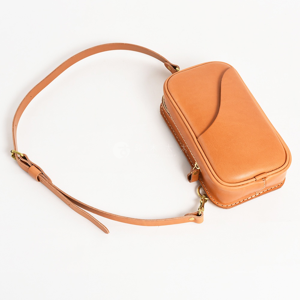 日本HERZ職人手作駝色皮革兩用直立型斜背包，頂部有拉鍊開合，正面有一個曲線形插袋，附有可拆卸調整的長背帶，以白色縫線手工製作。