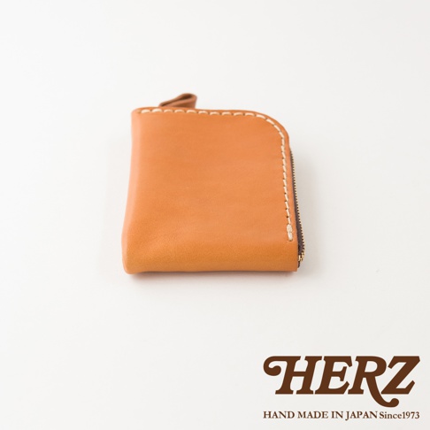 日本HERZ職人手作皮革分隔收納迷你錢包，採用天然色皮革製成，表面呈現細緻質感，側面為拉鍊開口設計並搭配粗縫線細節，整體外觀呈現簡約溫潤的日式手工藝風格。