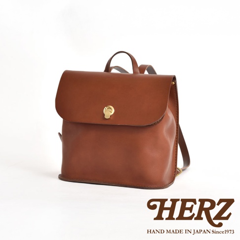 一個棕色皮革迷你後背包，有翻蓋設計和金色扣環，附有雙肩帶。