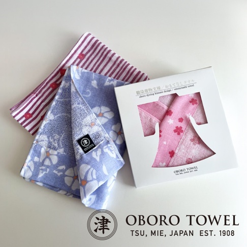 視覺描述模式 三條日式花紋毛巾，其中兩條為淡紫色碎花圖案，一條為紅色條紋搭配紅色圓點，置於白色禮盒旁。