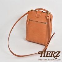 淺棕色皮革迷你軟皮杜勒斯包，配有可調節肩帶、頂部提把及前方拉鍊口袋，整體以白色背景呈現，品牌Logo標示於下方。