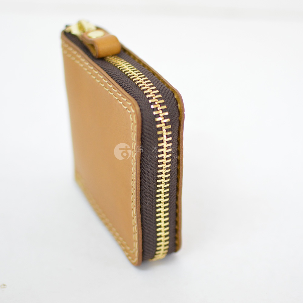 一個側面角度拍攝的日本HERZ職人手作皮革全包式拉鍊短夾，採用淺褐色Latigo軟皮革材質，搭配深褐色布邊與金色金屬拉鍊，呈現簡約耐用的質感，邊緣縫線工整細膩。