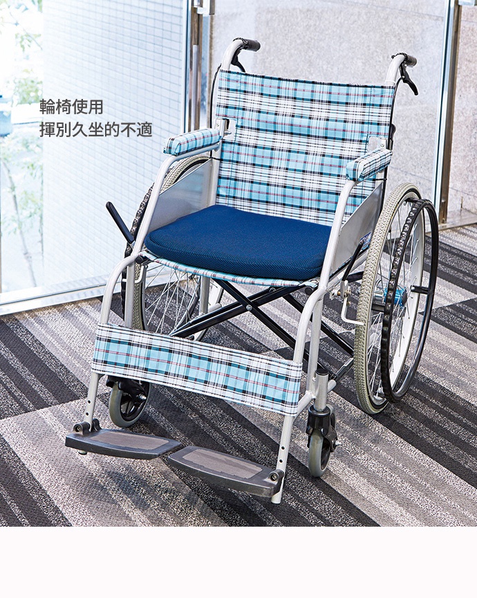 輪椅上放置一個深藍色蜂巢式坐墊，坐墊上有紋理，輪椅骨架為銀色，椅背和扶手為藍色、白色、黑色格紋布套。