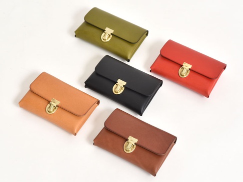 五個職人手作皮革小卡片收納夾，有綠色、黑色、紅色、棕褐色和淺棕色，皆配有金色旋轉鎖扣。