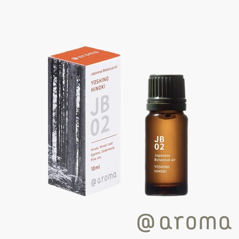 日式本真系列-JB02 吉野檜木精油。琥珀色玻璃瓶裝，深綠色瓶蓋。產品標籤為白色，印有黑色和灰色文字，標示「JB 02」、「Japanese Botanical air」、「YOSHINO HINOKI」及「10ml」。產品盒為白色，側面印有森林黑白圖案，頂部為橙色。