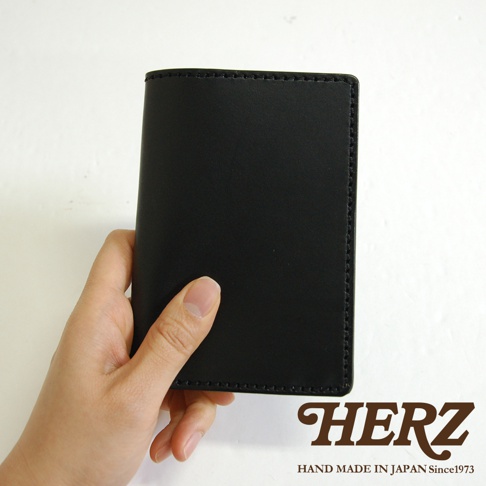 一手持黑色皮革經典護照套，縫線清晰，材質光滑。