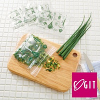 透明塑膠密封保鮮袋，印有綠色蔬菜圖案，內含切碎的蔥，另有一疊未開封的同款保鮮袋。右側擺放一束新鮮青蔥，旁邊是木質砧板和一把刀。