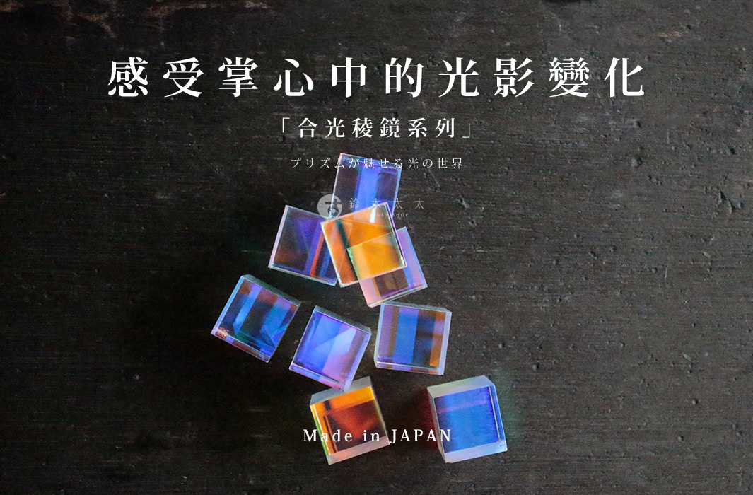 一堆透明玻璃稜鏡立方塊，表面呈現彩虹般的光澤，散落在深色木紋背景上。