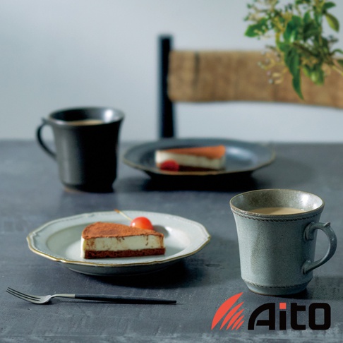 Aito 品牌下，兩塊日式提拉米蘇蛋糕，搭配兩杯咖啡，擺放在灰色桌面上的兩個盤子裡，其中一個盤子裡有兩個切塊，另一個盤子裡有一個切塊，旁邊有一支餐叉，右側有一個藍灰色的馬克杯，杯身有編織般的紋路，左側還有一個黑色的馬克杯，圖片下方有 Aito 的 Logo
