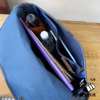 藍色純棉帆布雙扣郵差包，內部裝有紫色文件夾、水瓶、筆記本、筆和一個棕色皮革錢包。