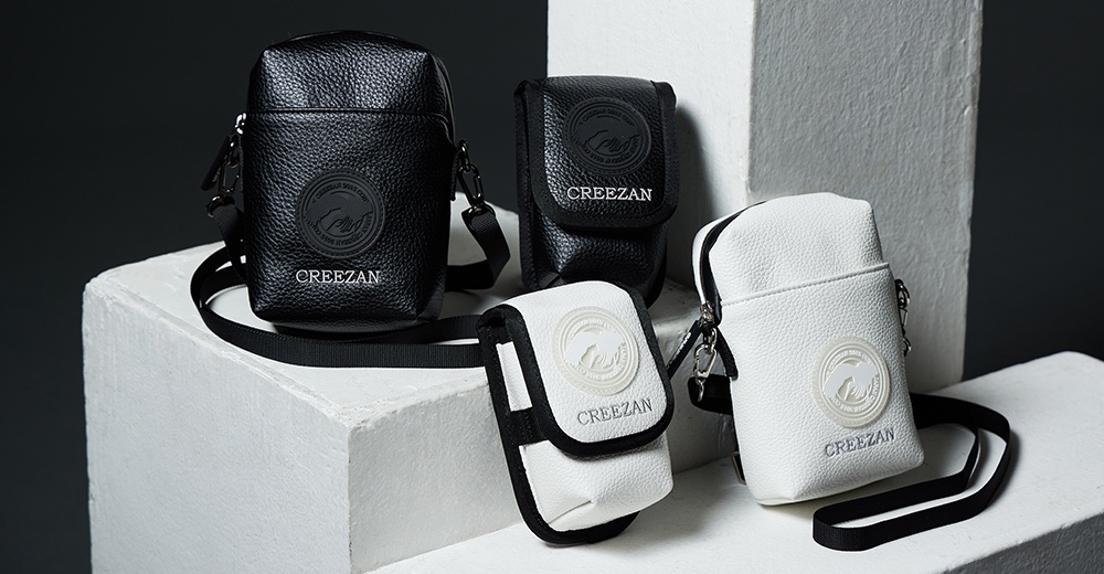 四款高爾夫方形側背包，材質為荔枝紋皮革，顏色有黑色與白色。兩款黑色側背包，一款較大，帶有同色系的圓形品牌標誌；另一款較小，同樣有品牌標誌。兩款白色側背包，一款較大，帶有白色圓形品牌浮雕標誌；另一款較小，為白色翻蓋設計，有白色圓形品牌浮雕標誌。皆配有黑色斜背帶。