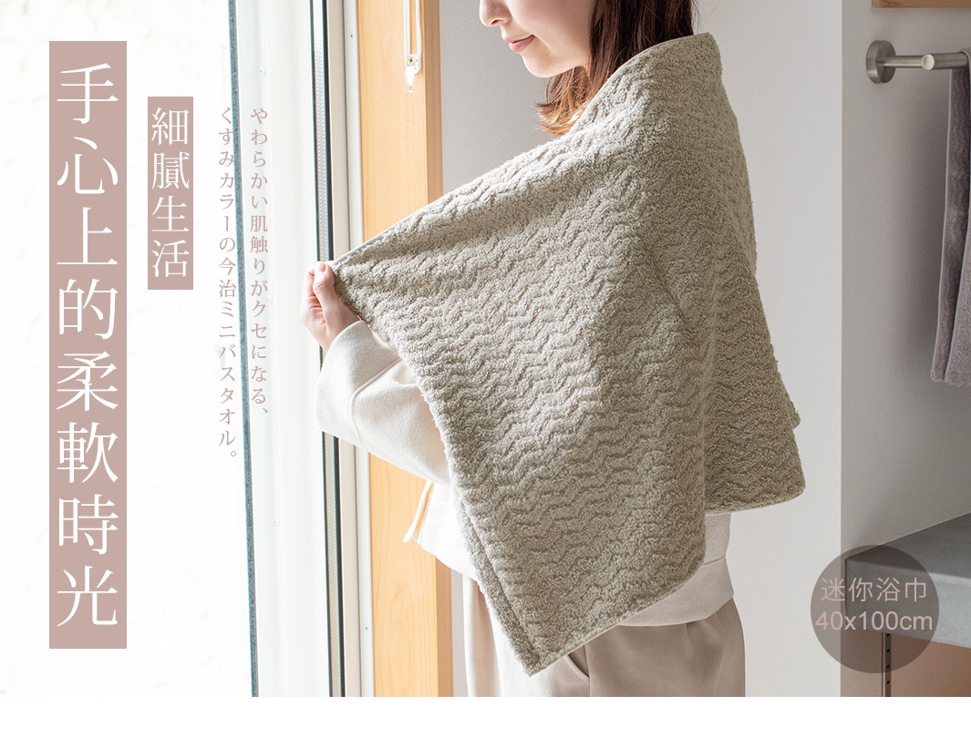 Broome ASH 今治柔韻波紋甘撚迷你浴巾 40x100cm，米色毛巾上飾有精緻的波浪緹花紋理，一位女士肩披毛巾，展現其柔軟觸感。