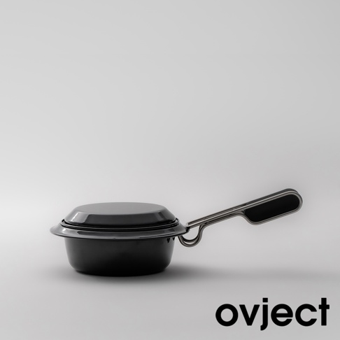 黑色琺瑯湯鍋，帶有一個可折疊的銀色金屬手柄，鍋蓋與鍋體緊密貼合，整體造型簡潔，置於淺灰色背景上。