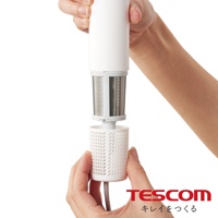 一手正在拆卸吹風機的白色濾網蓋，另一手握持吹風機主體，露出內部金屬網狀結構。