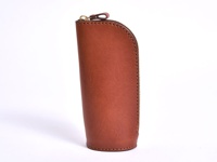 職人手作皮革直立式收納筆袋，採用經典棕色皮革製成，帶有金屬拉鍊和皮革拉環，縫線整齊，整體呈現簡約復古風格。