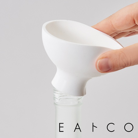 白色陶瓷漏斗，一隻手握持，將漏斗置於玻璃瓶口。