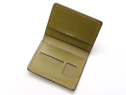 橄欖綠皮革雙折證件夾，內有三個卡槽，其中兩個卡槽上方有開口，一個卡槽下方有透明窗口，縫線精緻，品牌標誌壓印在內側。