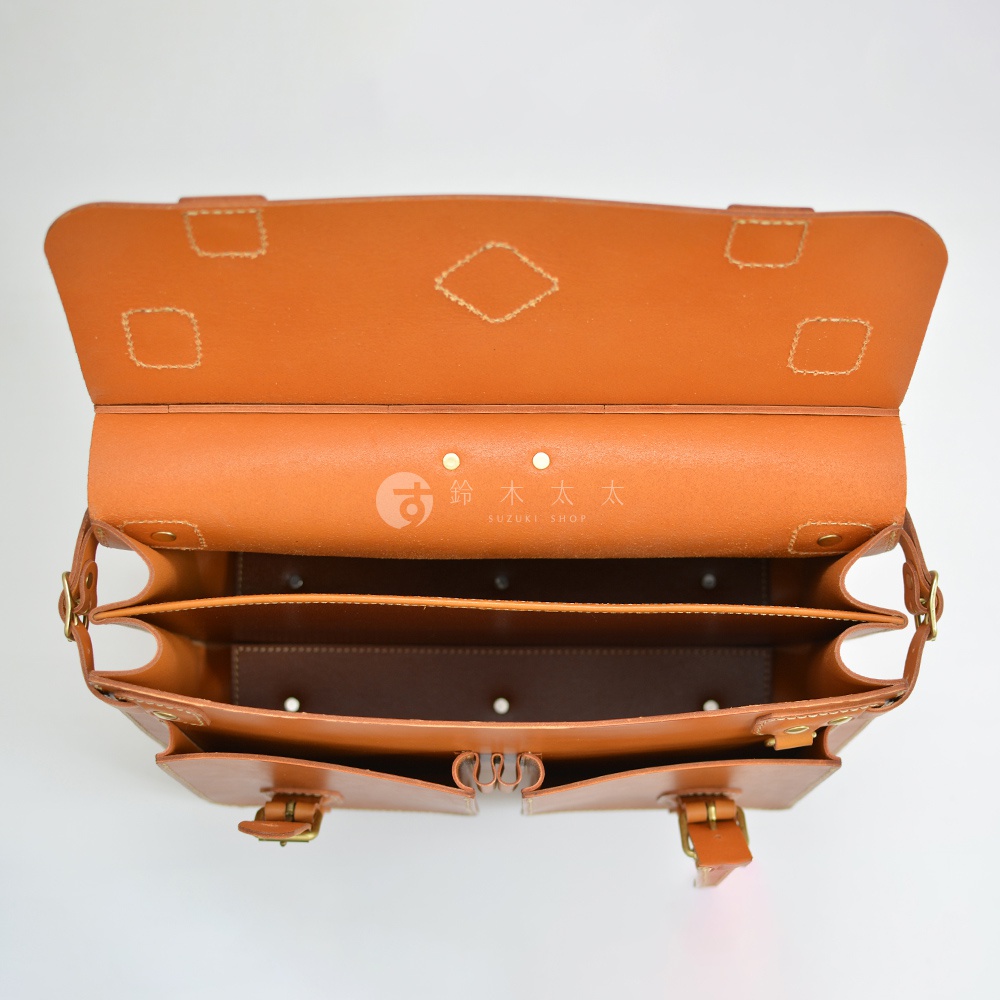 職人手作皮革旅行包 A-102，呈現經典棕色，採用天然皮革材質。包款內部結構清晰，有分隔層設計，外觀簡約，配有金屬扣環與皮帶。