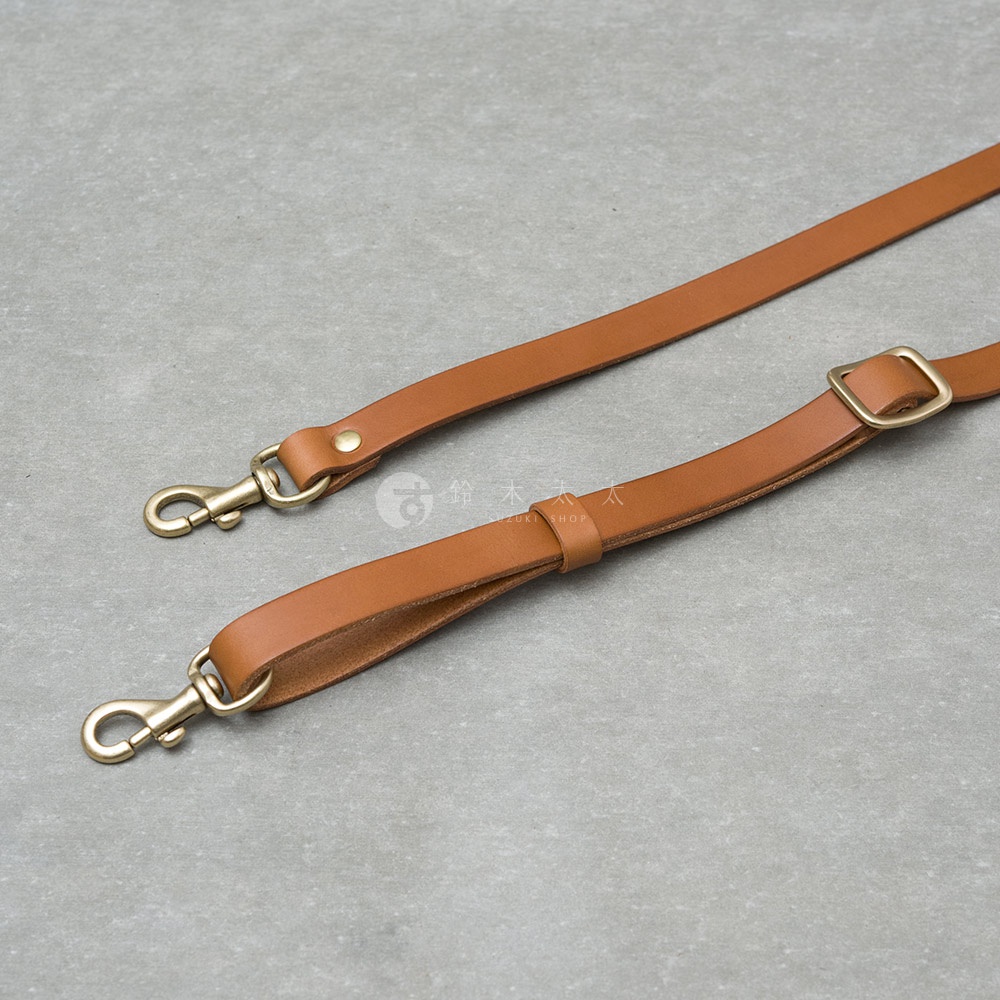 兩條咖啡色皮革揹帶，一條末端有金色鉤扣，另一條末端有金色鉤扣及方形調節環，皆為職人手作。