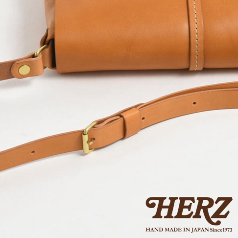 日本HERZ品牌手工製作的淺棕色皮革馬鞍包，特寫其可調節的肩帶和精緻的扣環細節。