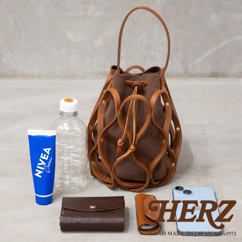 日本HERZ職人手作Organ編織水桶包，搭配NIVEA護手霜、鑰匙包、iPhone手機與水瓶，展現都會女性的日常隨身配件。