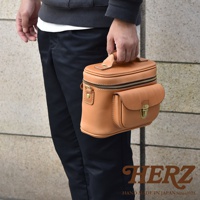 棕色皮革相機包，箱型設計，配有拉鍊主隔層與前方翻蓋口袋，口袋上飾有金屬鎖扣。