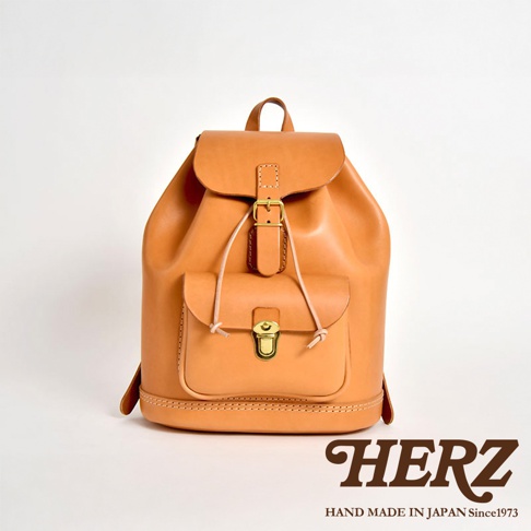 經典款棕色皮革後背包，採用全皮革製作，配有金屬釦和抽繩閉合。