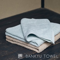 疊放的兩條毛巾，一條為淺藍色，一條為淺棕色，毛巾表面有細緻的長纖維，質地柔軟。