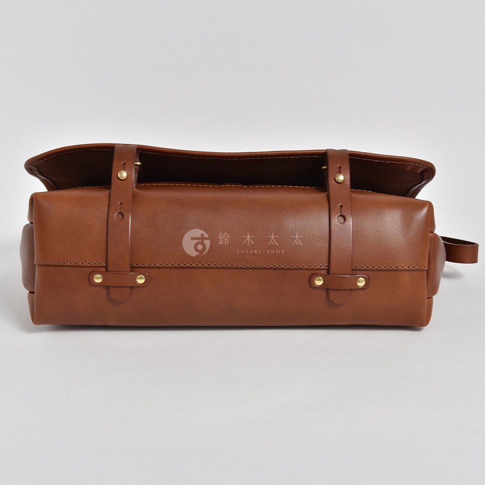 職人手作皮革復古郵差包 CM-100，採用棕色牛皮製作，包身方形設計，配有兩條皮質揹帶，以金色銅釦固定，整體風格簡約復古。