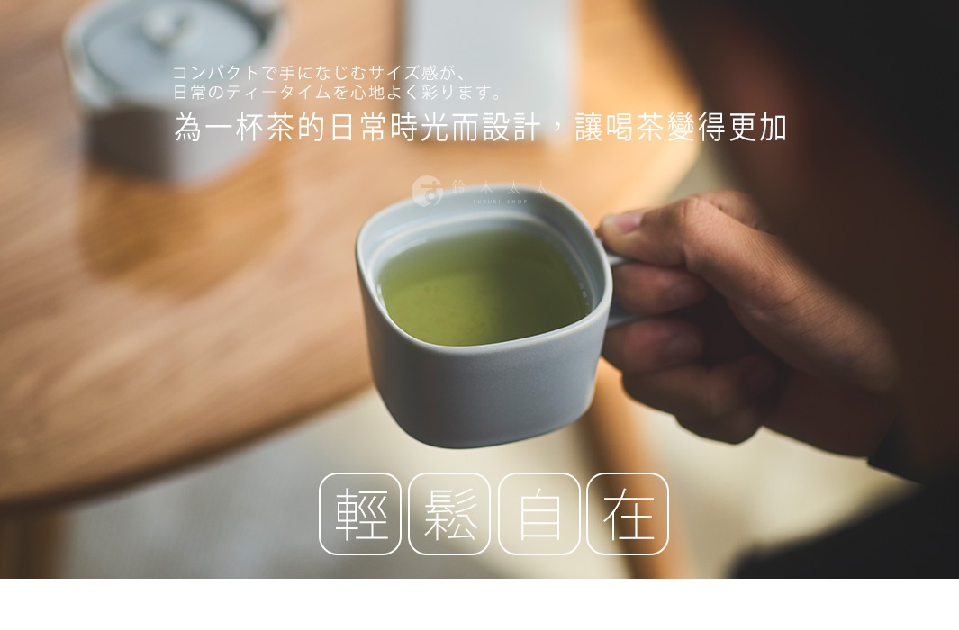 一個人手持淺灰色方形美濃燒馬克杯的特寫，杯中裝有綠茶，背景為溫潤木質桌面的日常飲茶場景，圖片中帶有日文與中文設計文案，傳遞著輕鬆自在的生活感。