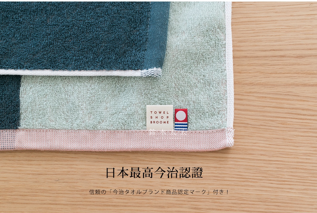 今治KAKUTERU純棉毛巾，以深藍、淺綠、粉紅三色色塊拼接設計，質地柔軟，帶有品牌標籤。
